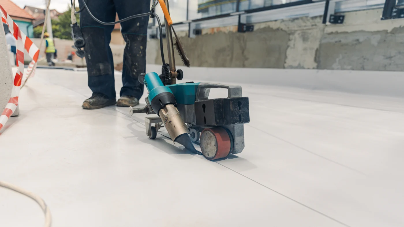 A roofing contractor uses equipment to install a TPO roof