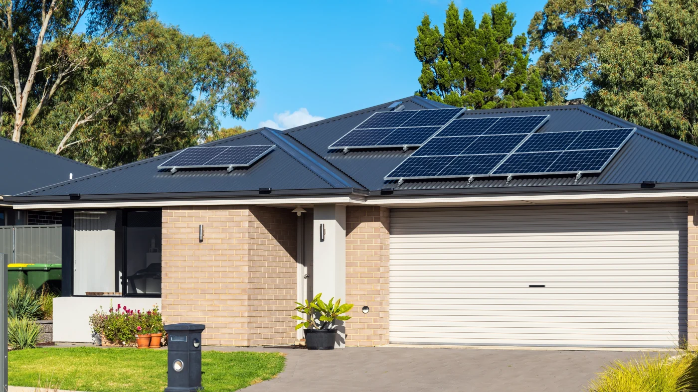 A one-story brick home with a black roof and solar panels