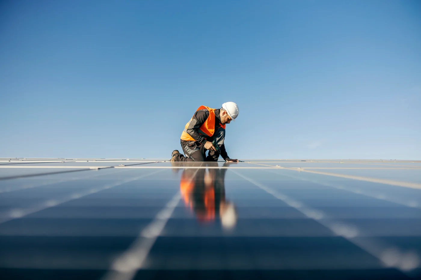 A roofer finishes installing solar panels.