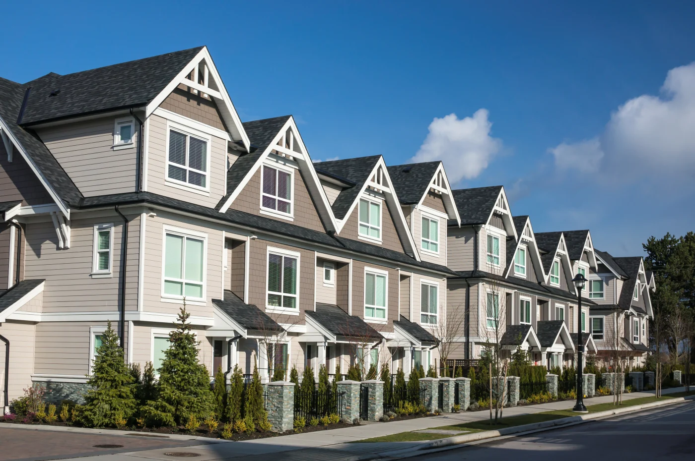 A row of modern townhomes with black shingle roofing.
