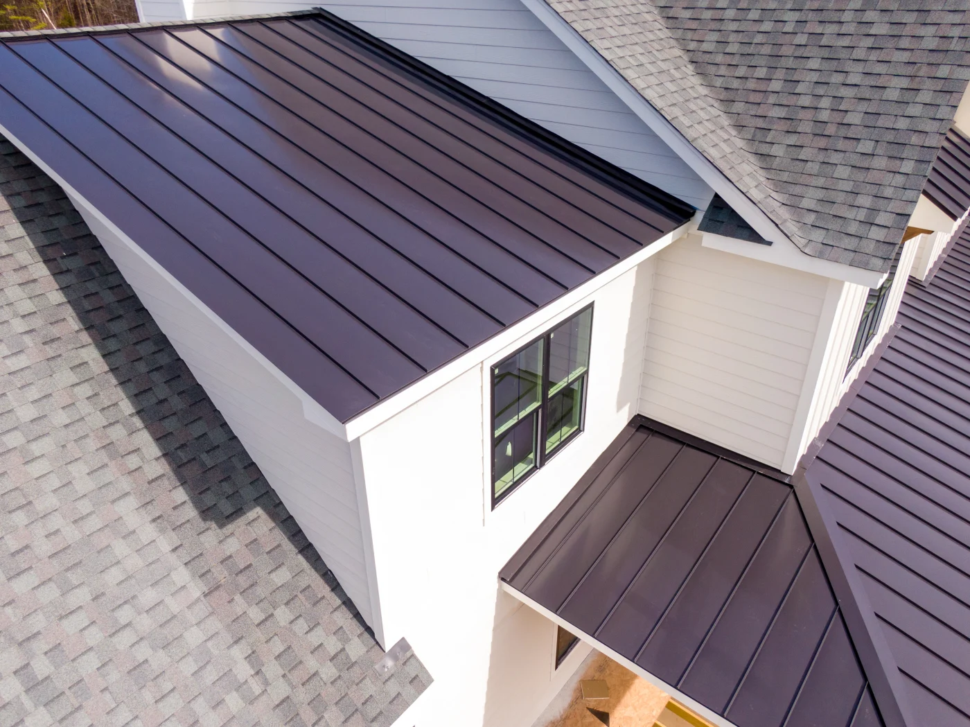 A home with white siding and metal and shingle roofing sections.