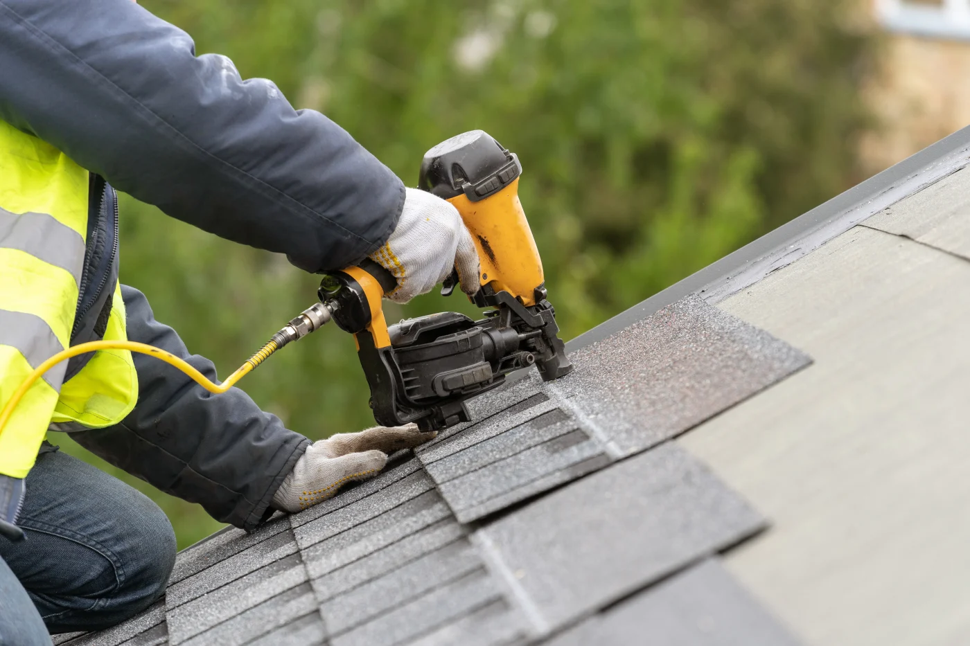 Professional roof repair technician repairing damaged shingles on a residential home in Longmont, Colorado.