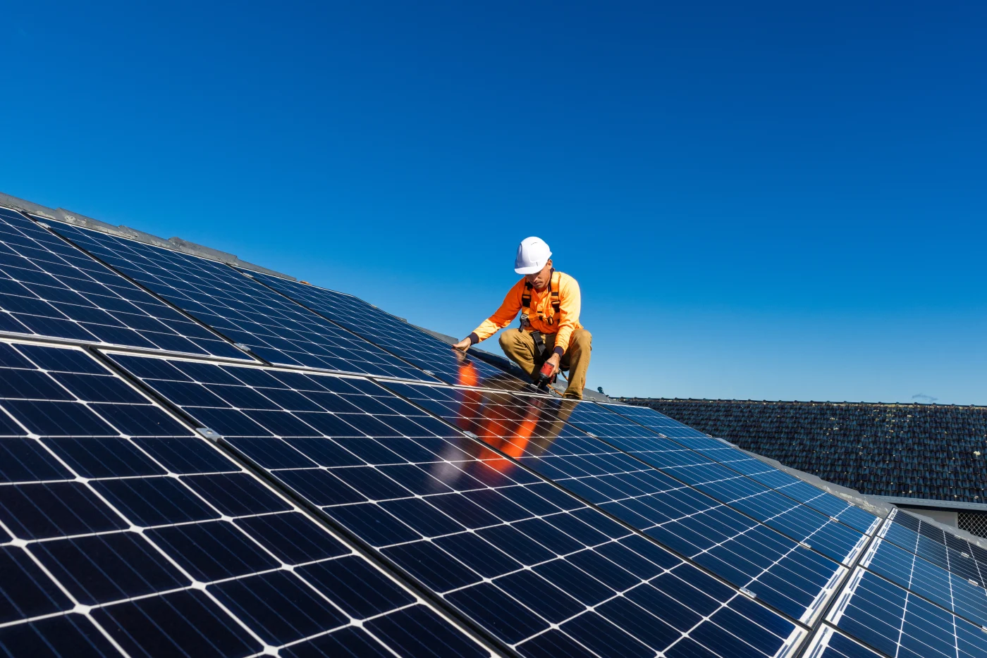 A roofer completes a solar panel installation.