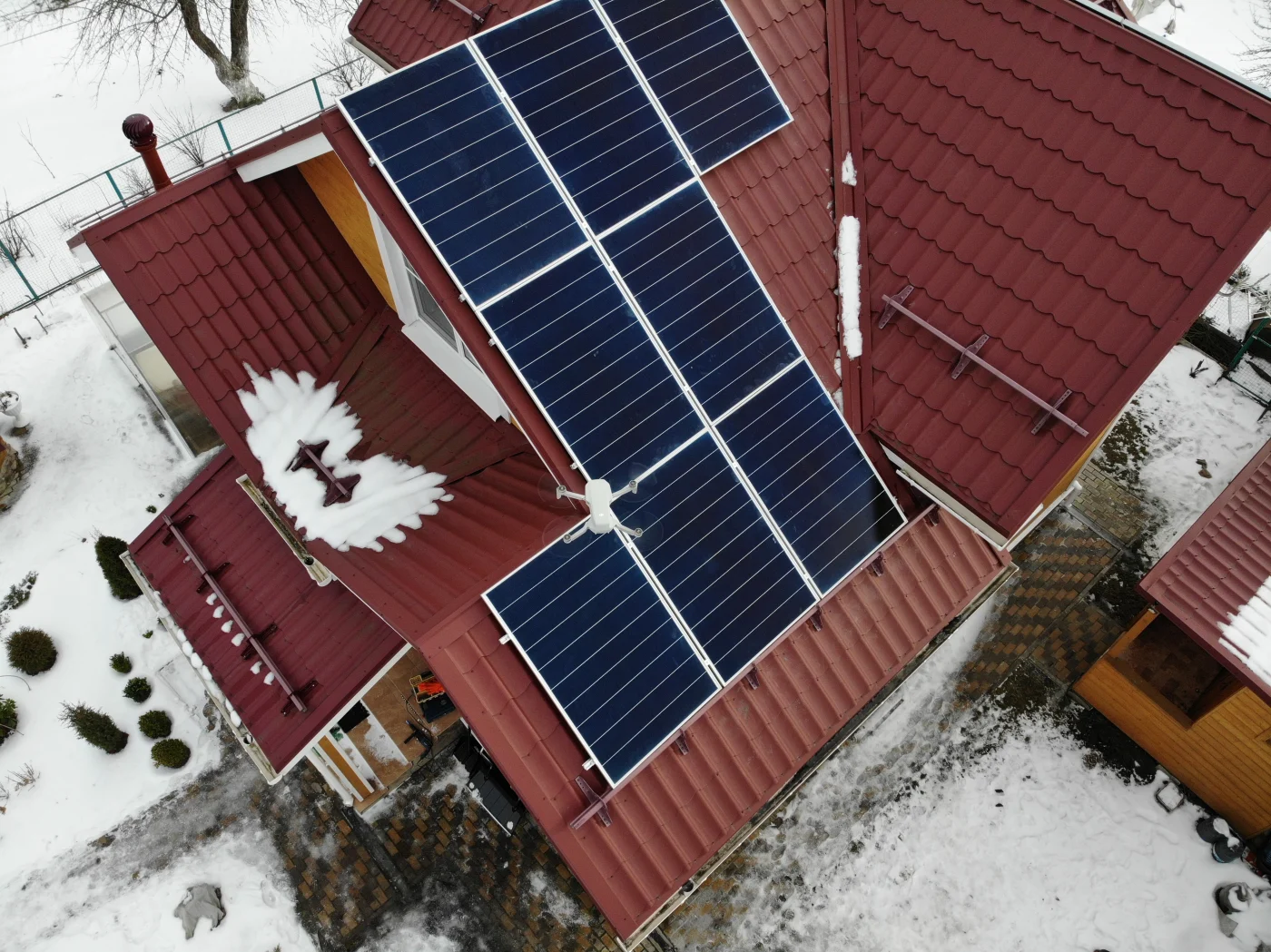 Aerial view of a red metal roof with several blue solar panels installed on top of a home in Boulder, CO.