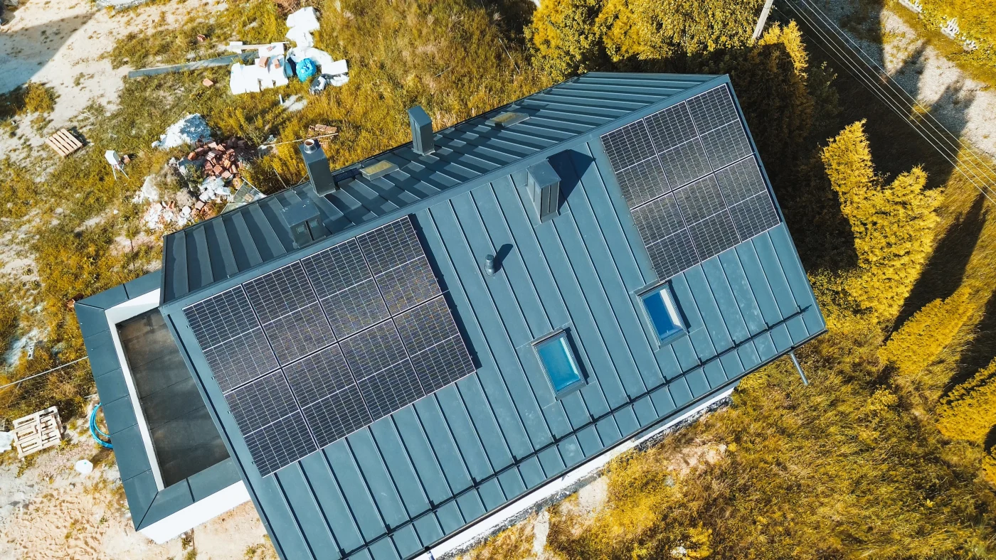 Aerial view of a modern home in Boulder, CO, with a sleek dark metal roof featuring two arrays of solar panels