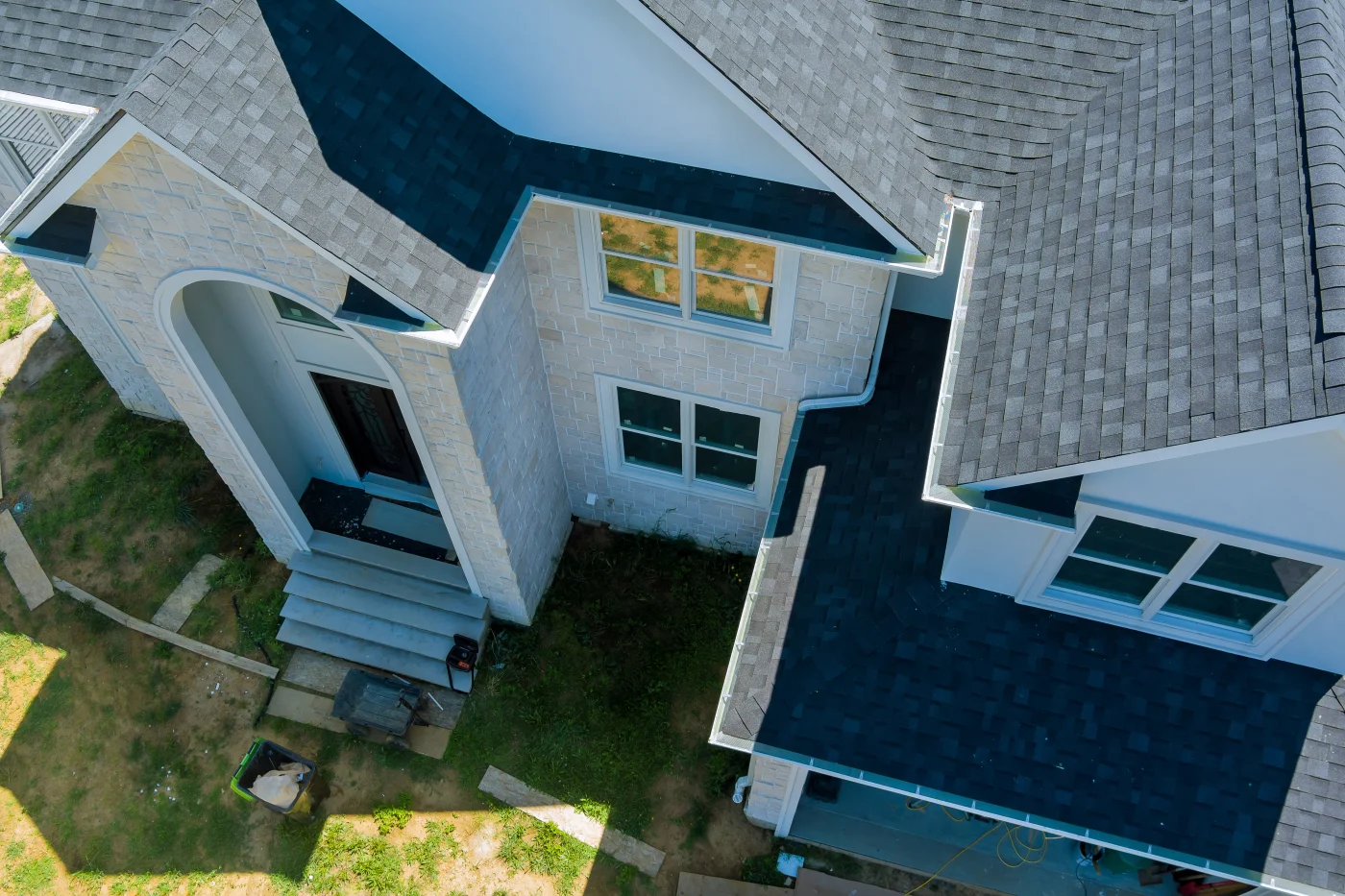 Aerial view of a white home with a new black asphalt roof installed.