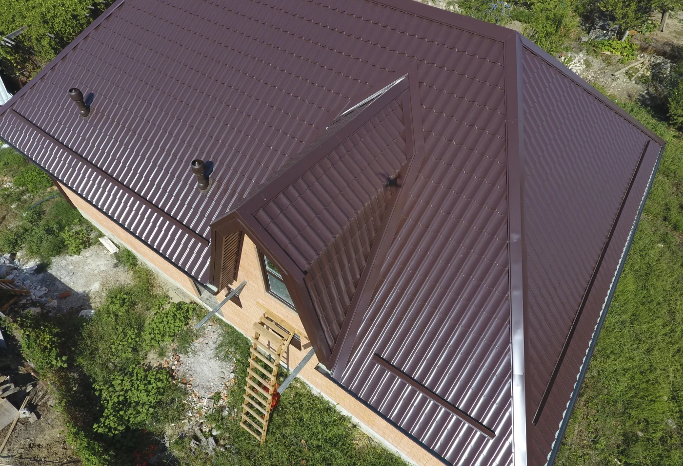 Aerial view of a home with burgundy metal roofing installed.
